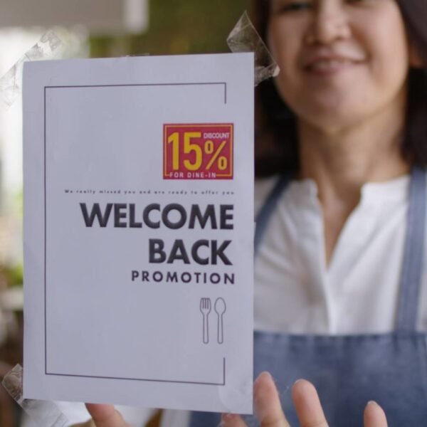 Discount campaign banner in asia bakery cafe coffee shop after post covid-19 coronavirus pandemic. Happy woman work smile stick label text placard logo on door glass. SME buying coupon offer.